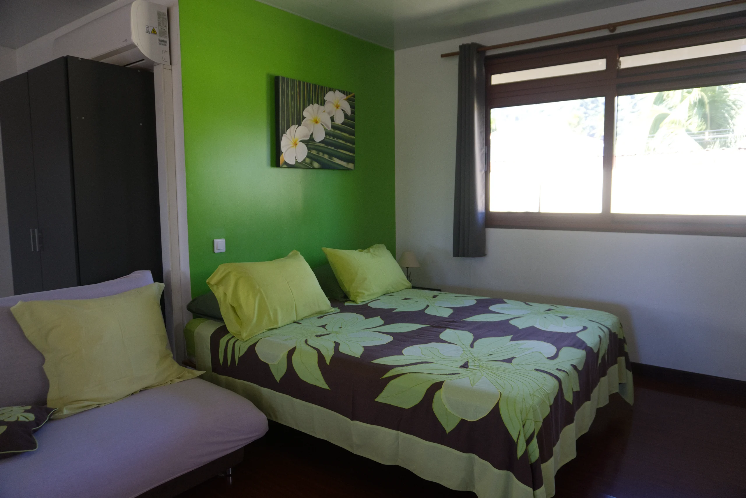 B.TARE lit - Teahupo'o, Tahiti Le bungalow Tiare, mur vert, tifaifai vert et brun.