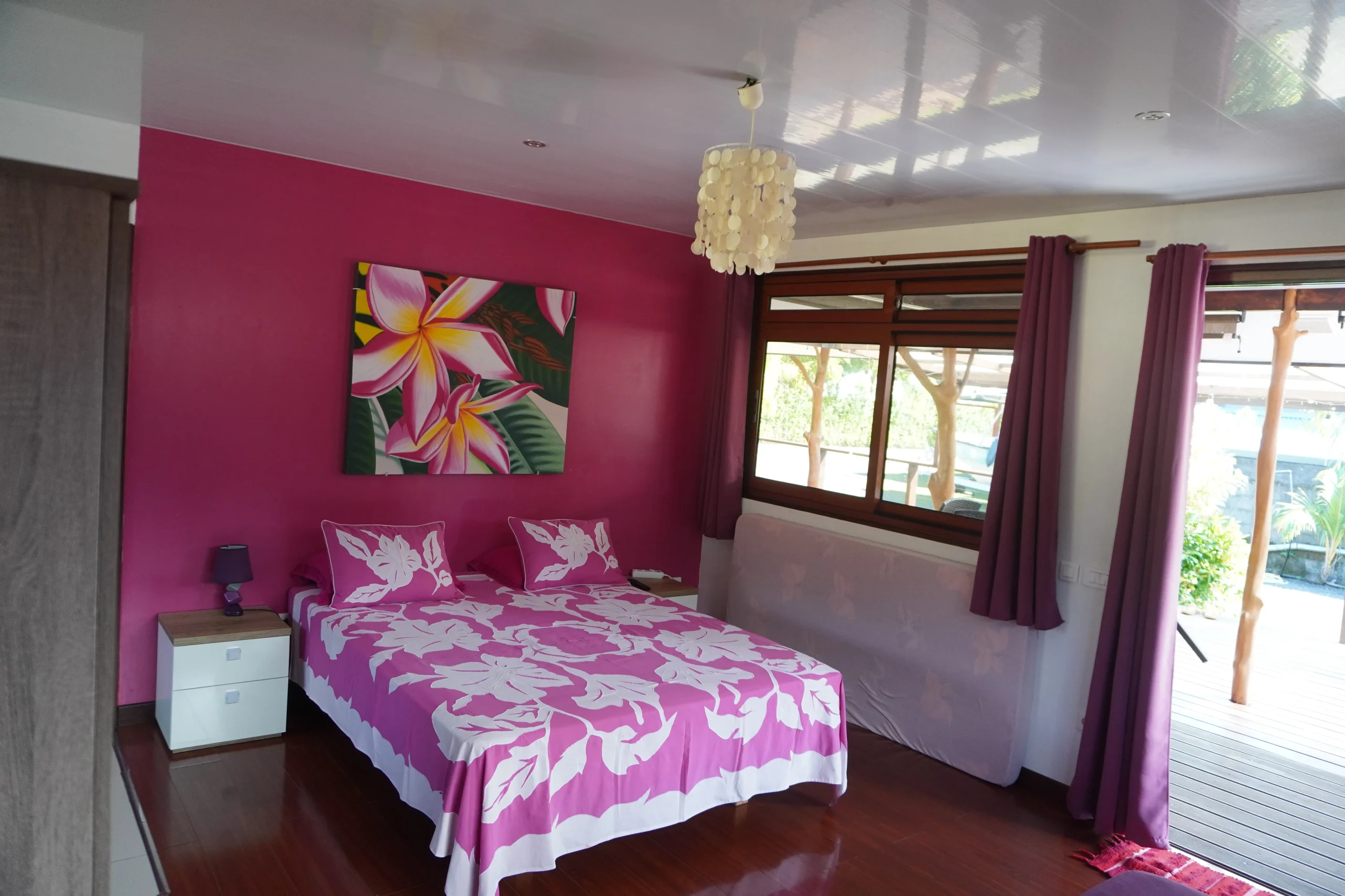 B.TIPANIER lit Le bungalow Tipanier, mur fuchsia, tifaifai violet et rose.